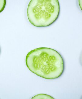 Close-up of fresh cucumber slices in a flatlay pattern on a white background.