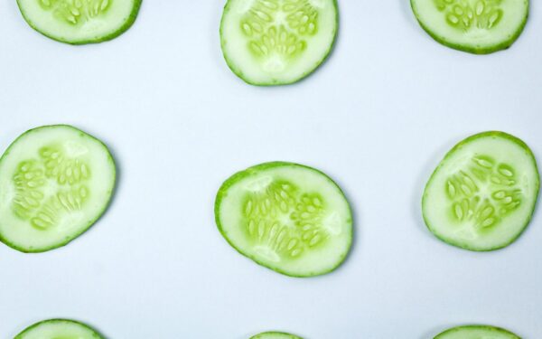 Close-up of fresh cucumber slices in a flatlay pattern on a white background.