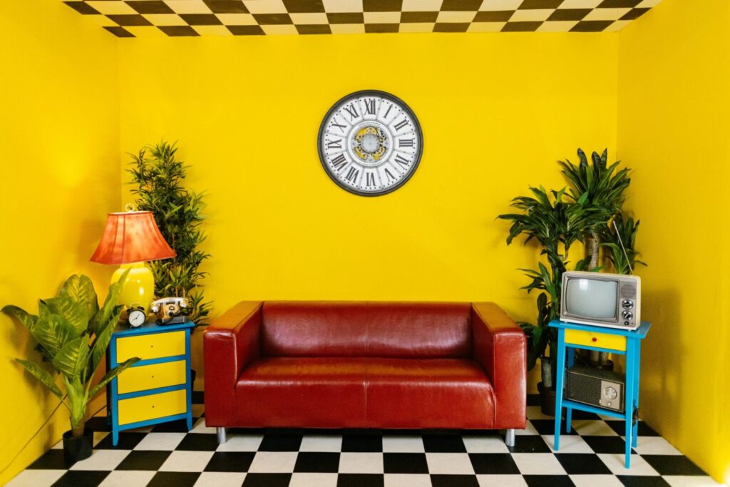 Vibrant yellow room with a red couch, retro decor, and checkered floor.