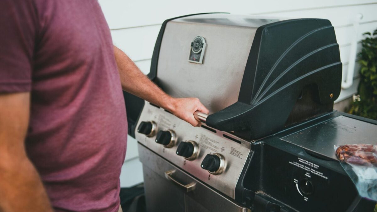 Adult man using a gas grill for outdoor cooking. Perfect summer barbecue scene.
