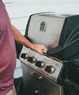 Adult man using a gas grill for outdoor cooking. Perfect summer barbecue scene.