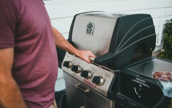 Adult man using a gas grill for outdoor cooking. Perfect summer barbecue scene.