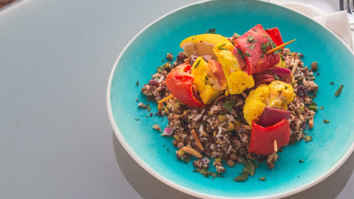 Vibrant quinoa salad topped with grilled vegetables on a blue plate.