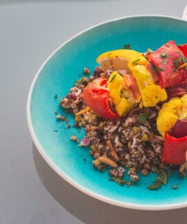 Vibrant quinoa salad topped with grilled vegetables on a blue plate.