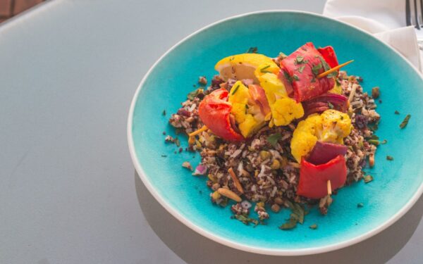 Vibrant quinoa salad topped with grilled vegetables on a blue plate.