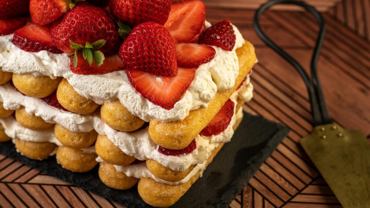 Layered strawberry shortcake topped with fresh strawberries and cream, perfect for sweet indulgence.