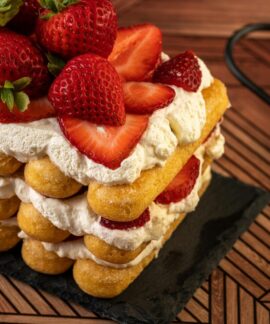 Layered strawberry shortcake topped with fresh strawberries and cream, perfect for sweet indulgence.