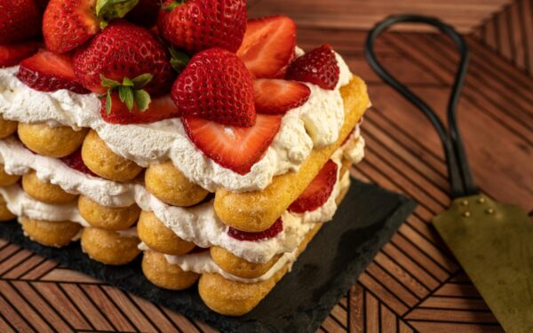 Layered strawberry shortcake topped with fresh strawberries and cream, perfect for sweet indulgence.