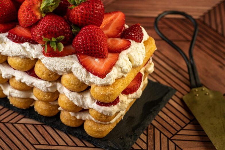 Layered strawberry shortcake topped with fresh strawberries and cream, perfect for sweet indulgence.