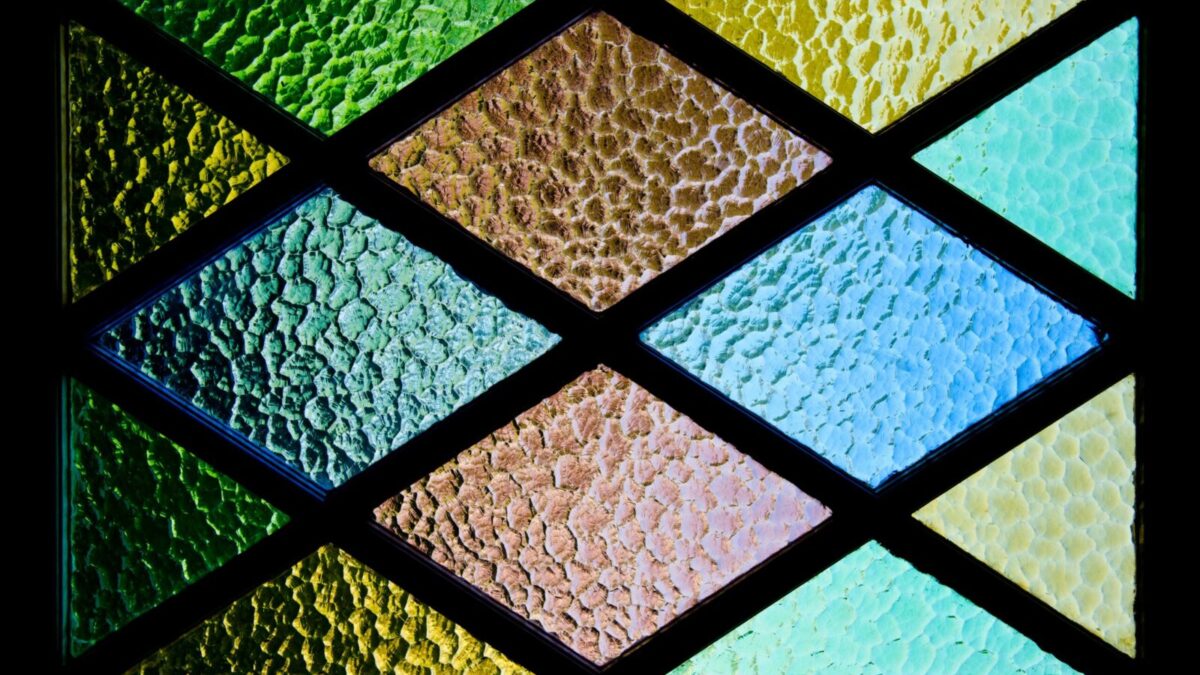 Vibrant stained glass featuring textured geometric patterns and colorful hues.