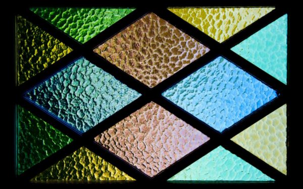 Vibrant stained glass featuring textured geometric patterns and colorful hues.