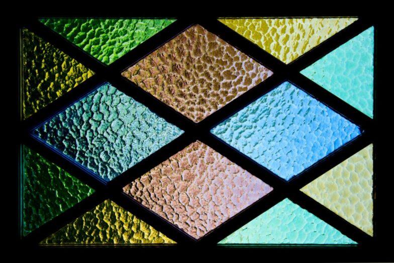 Vibrant stained glass featuring textured geometric patterns and colorful hues.