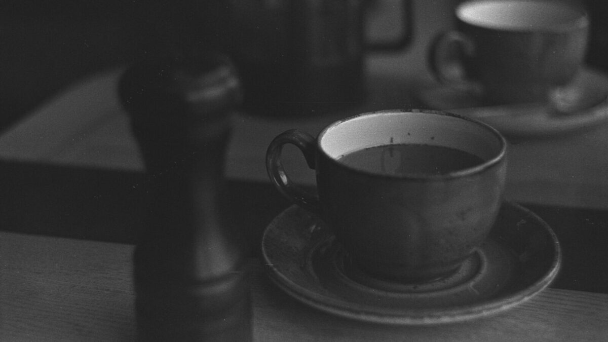 A classic black and white photograph of a coffee table with cups and saucer.