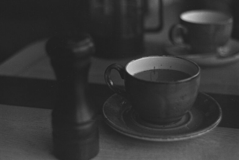A classic black and white photograph of a coffee table with cups and saucer.