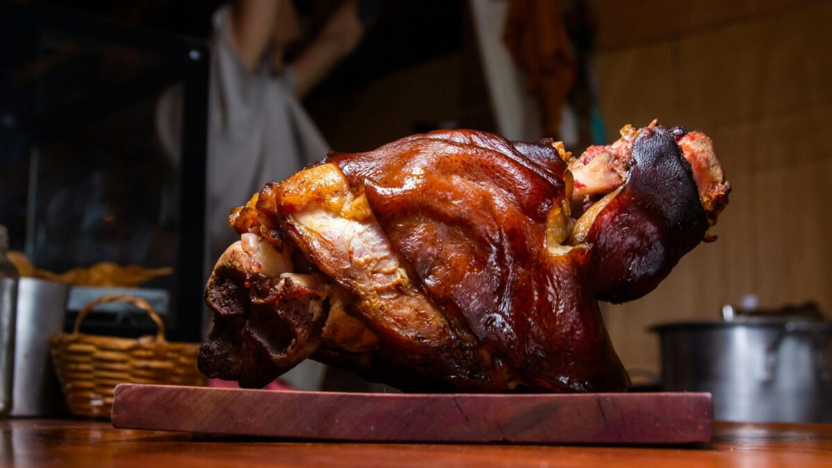 Close-up of a crispy roasted pork knuckle on a wooden cutting board, perfect for stock imagery.
