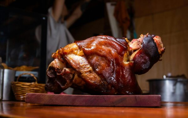 Close-up of a crispy roasted pork knuckle on a wooden cutting board, perfect for stock imagery.
