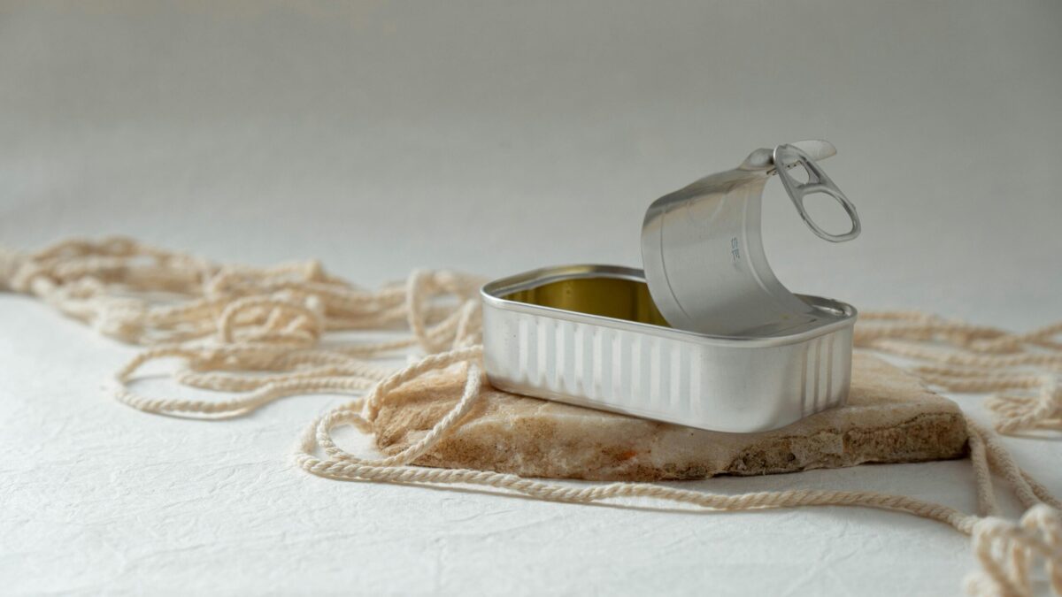 An open metal can rests artfully on a rock surrounded by string, creating a minimalist composition.
