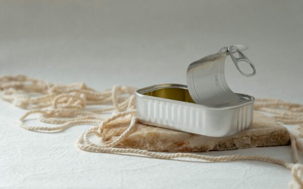 An open metal can rests artfully on a rock surrounded by string, creating a minimalist composition.