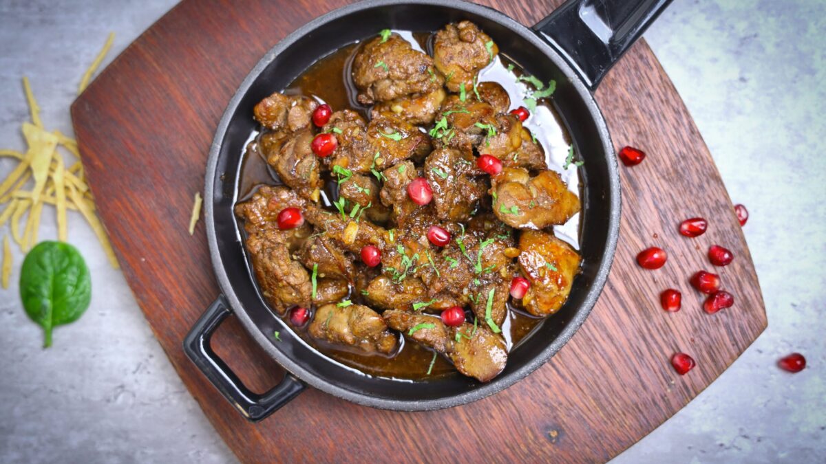 Delicious meat stew served with pomegranate seeds in a rustic pan.