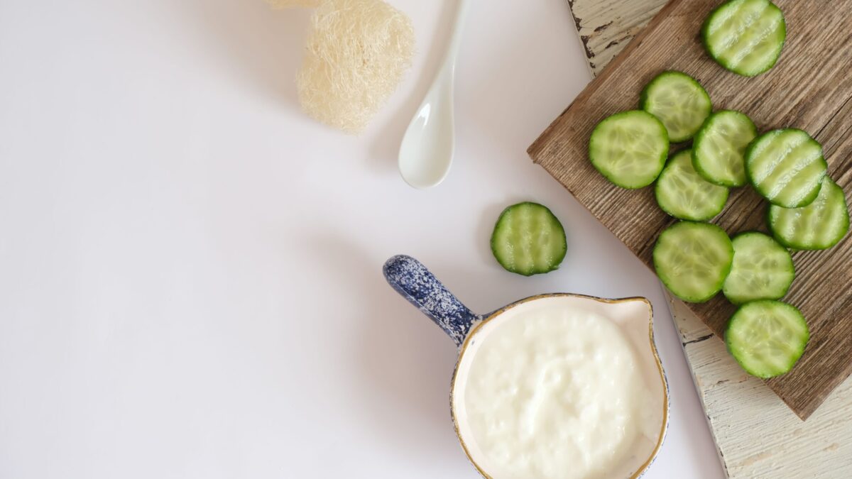 Top view of fresh cucumber slices and creamy yogurt on a rustic wooden board, ideal for healthy eating concepts.