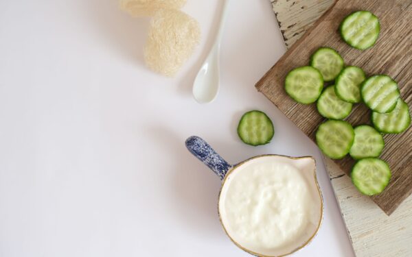 Top view of fresh cucumber slices and creamy yogurt on a rustic wooden board, ideal for healthy eating concepts.