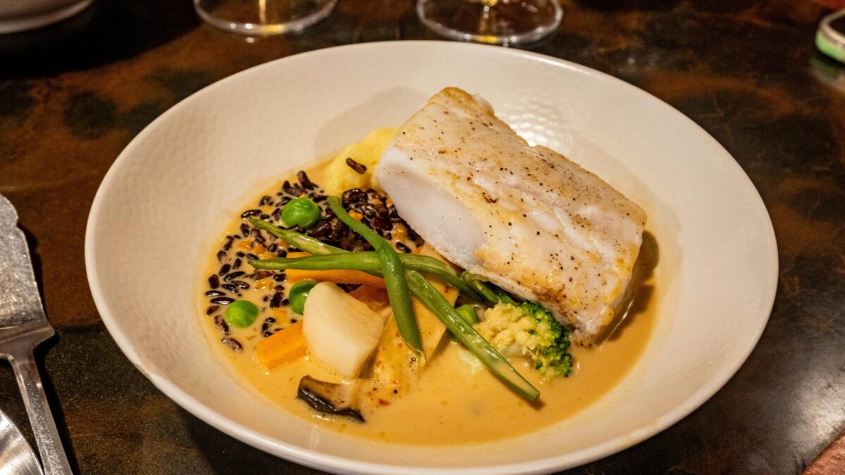 A delicious gourmet seafood dish featuring cod, vegetables, and creamy sauce.