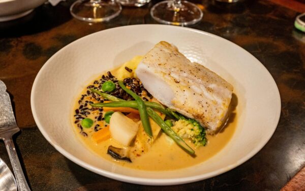 A delicious gourmet seafood dish featuring cod, vegetables, and creamy sauce.