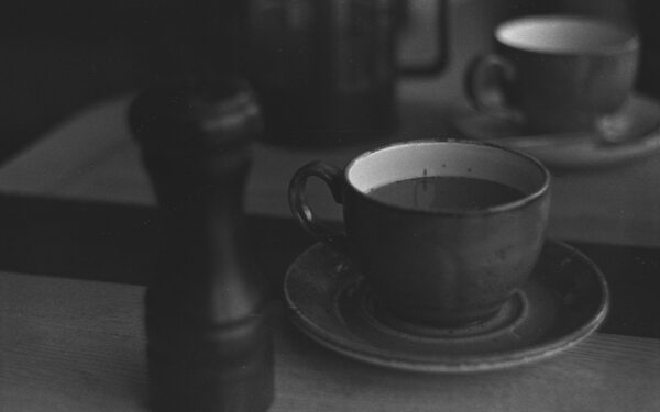 A classic black and white photograph of a coffee table with cups and saucer.