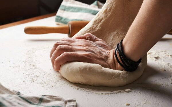 person making dough beside brown wooden rolling pin