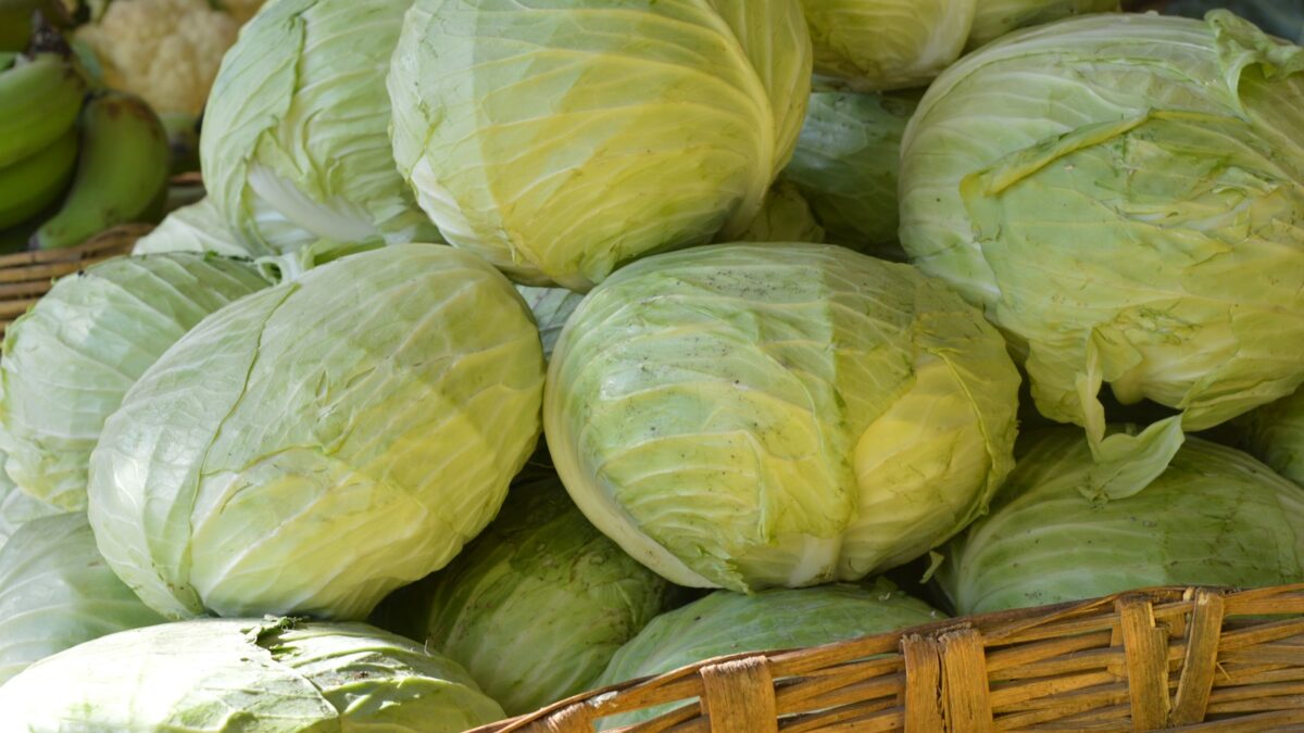 a basket filled with cabbage next to a pile of green apples