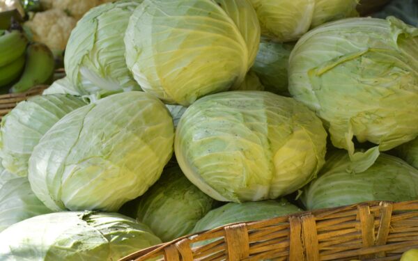a basket filled with cabbage next to a pile of green apples