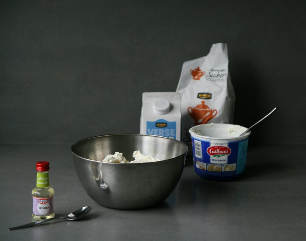 A metal bowl with a measuring cup and a spoon next to it