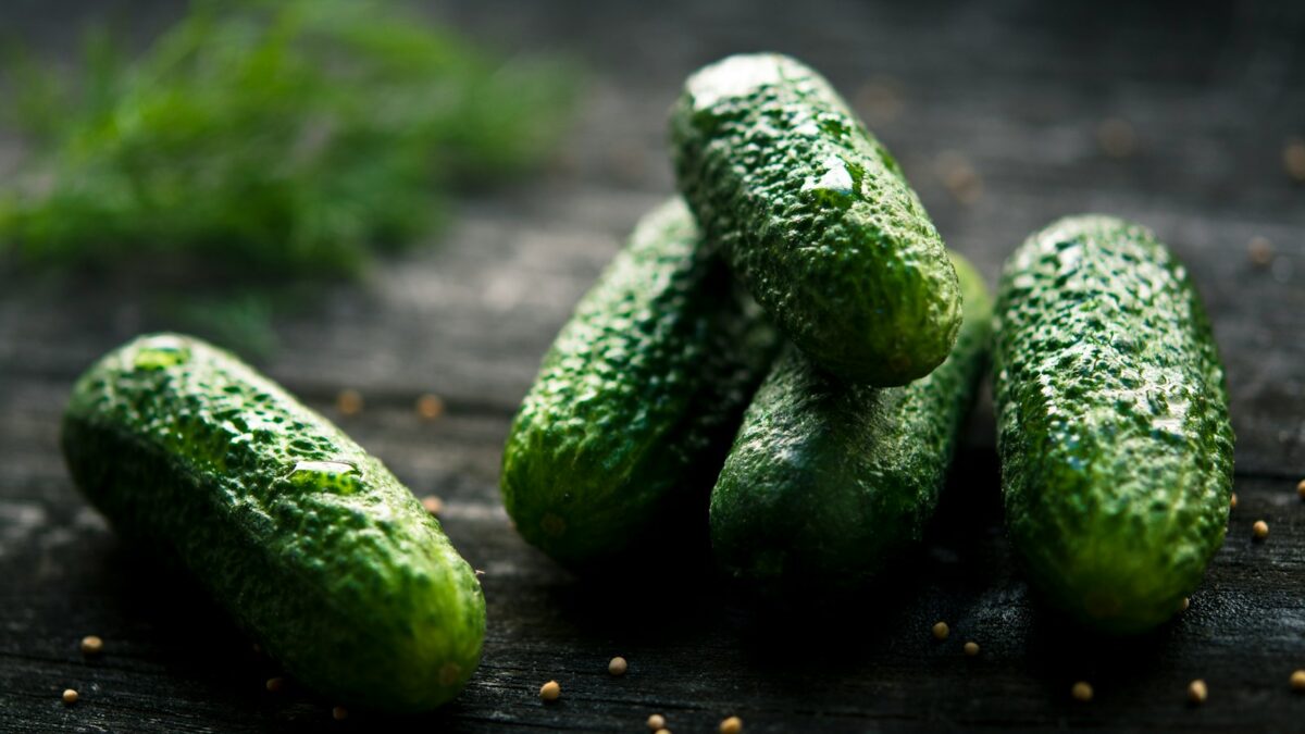3 green cucumbers on black wooden table