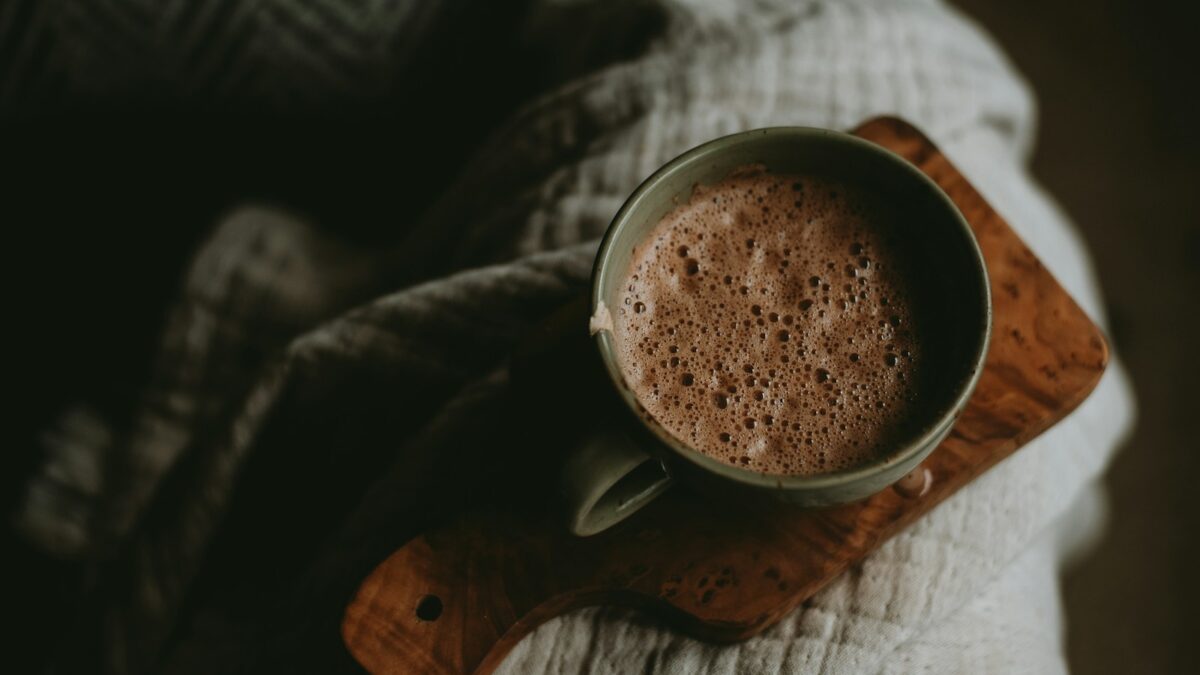 a cup of hot chocolate sitting on top of a wooden board