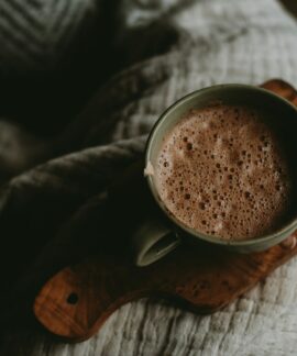 a cup of hot chocolate sitting on top of a wooden board
