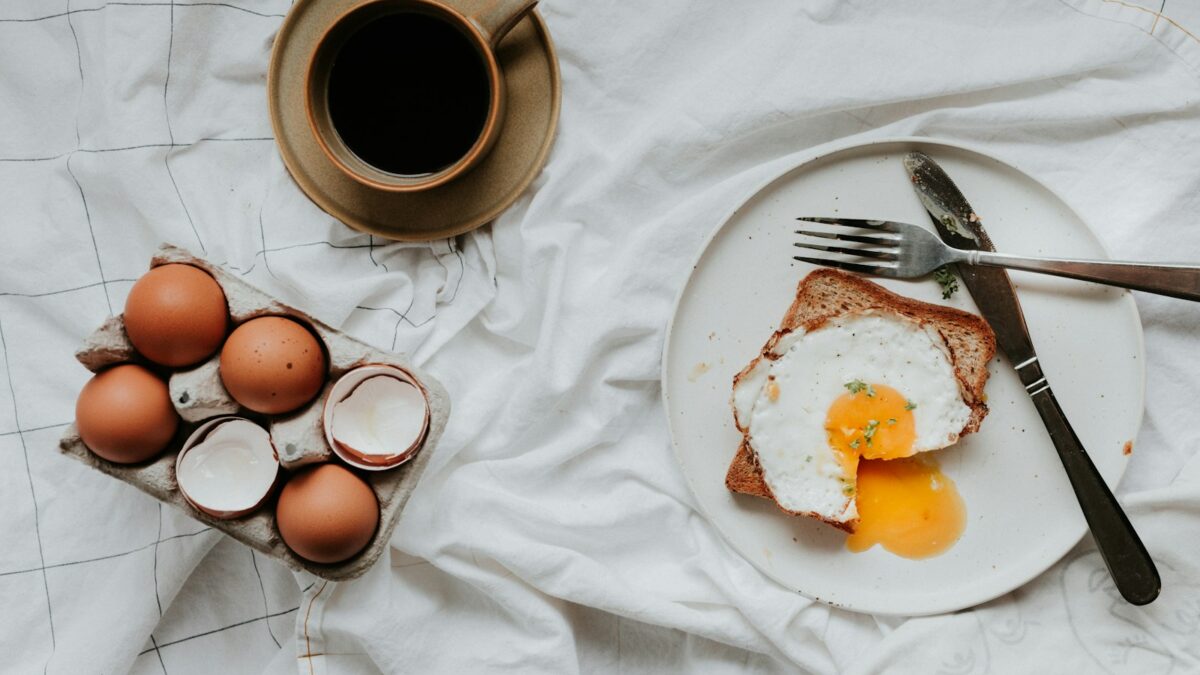 egg on white ceramic plate beside stainless steel fork and knife
