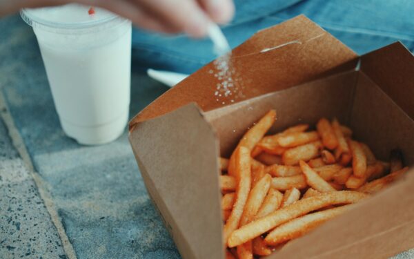 person sprinkling salt in fries