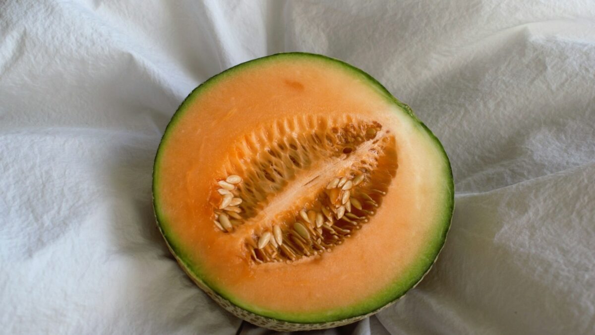 a cut in half melon sitting on top of a white cloth