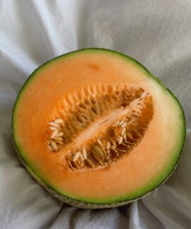 a cut in half melon sitting on top of a white cloth
