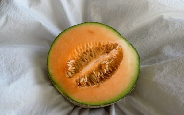 a cut in half melon sitting on top of a white cloth