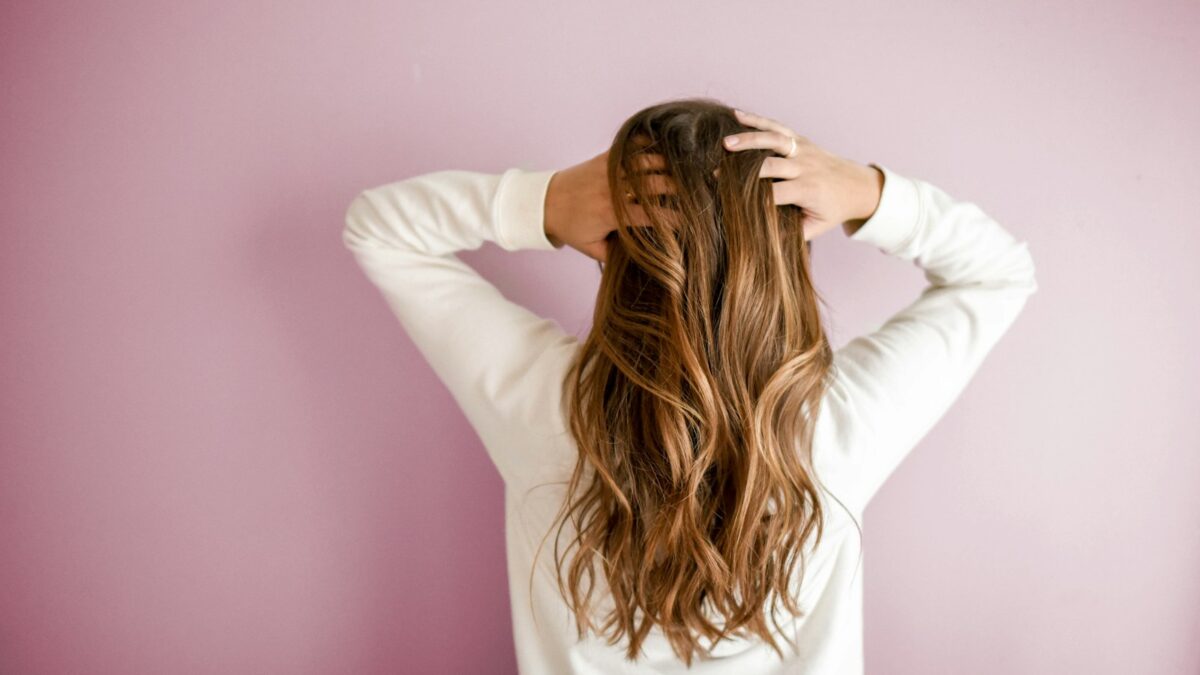 woman in white long-sleeved shirt standing in front of pink wall