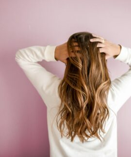 woman in white long-sleeved shirt standing in front of pink wall