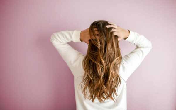 woman in white long-sleeved shirt standing in front of pink wall
