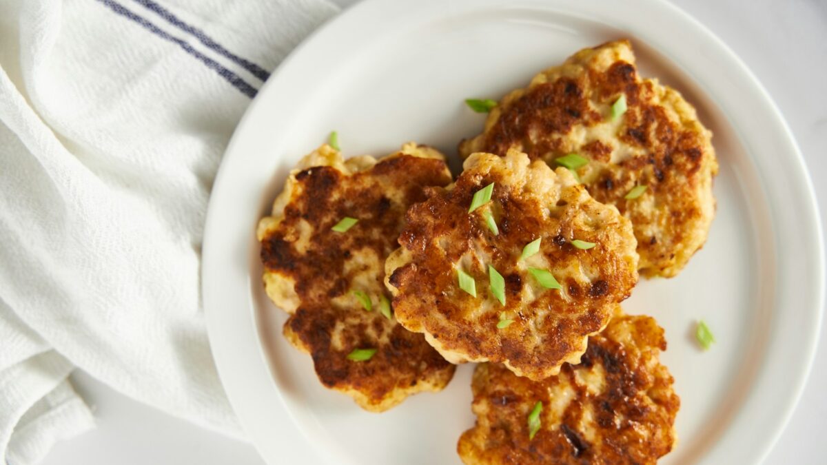 a white plate topped with crab cakes on top of a table