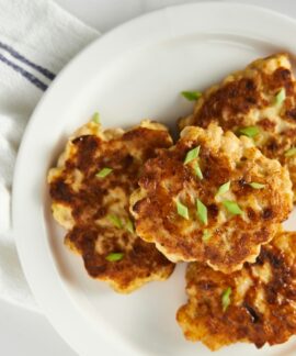 a white plate topped with crab cakes on top of a table
