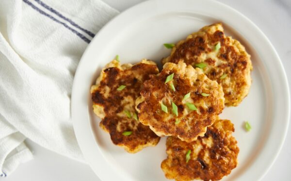 a white plate topped with crab cakes on top of a table