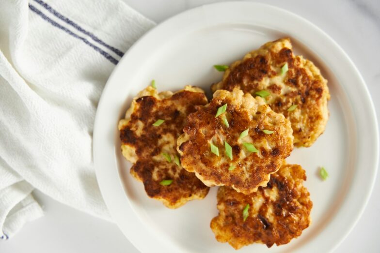 a white plate topped with crab cakes on top of a table