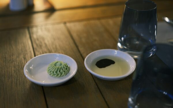 Two small dishes with sauce and wasabi