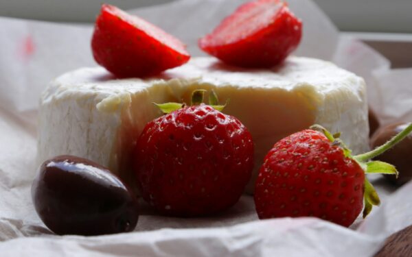Strawberries, cheese, and a chocolate truffle are shown.