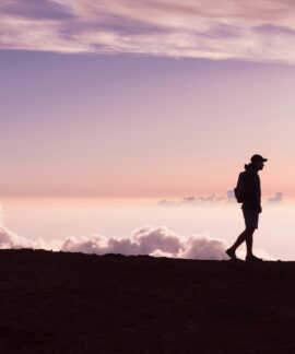 silhouette of person walking under white clouds